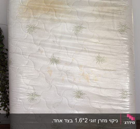 מזרן עם כתמים צהובים על רקע קיר לבן